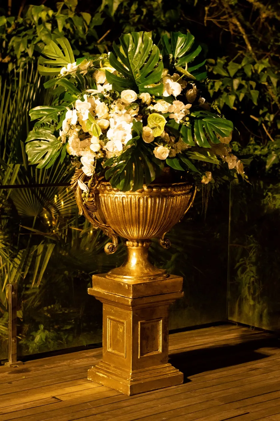 Arranjo de orquídeas em vaso dourado no deck